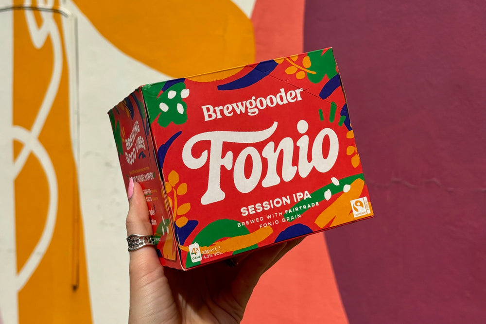 Hand holding a colorful box of Brewgooder Fonio Session IPA against a multicolored background