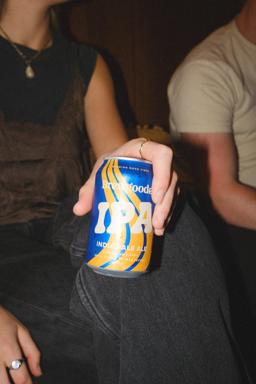 Person holding a can of Brewgooder IPA with blurred background, photo taken with a flash and edited in a 35mm film style